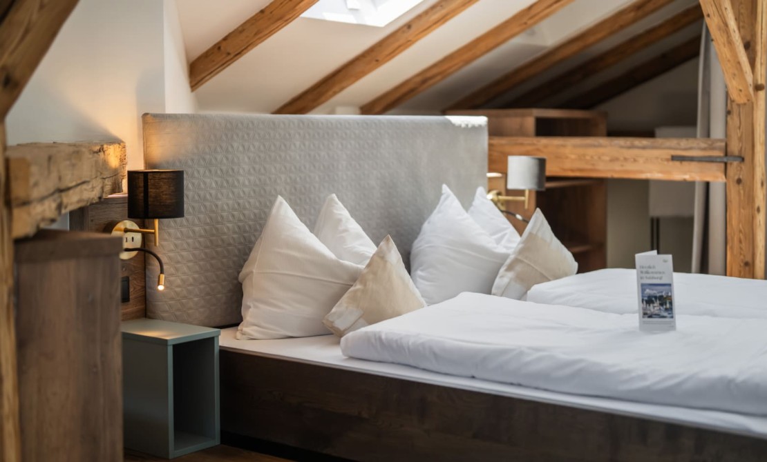 Schlafbereich mit Doppelbett und freiliegenden Holzbalken