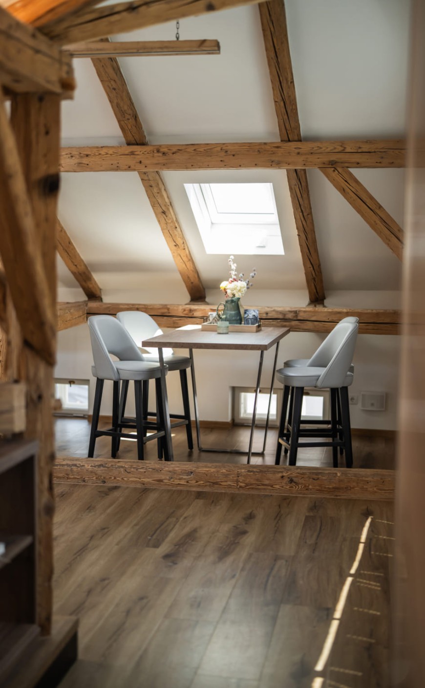 Essbereich der Loft Suite mit freiliegenden Holzbalken und Dachfenster
